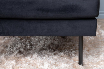 Navy blue sofa with a visible leg on a beige carpet